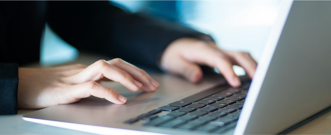 Close-up of hands typing on a laptop keyboard